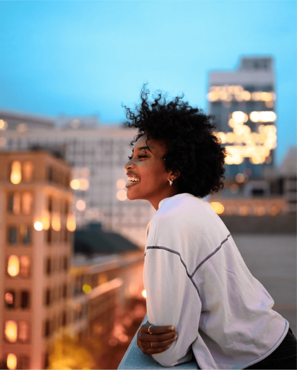 Smiling woman standing on a building rooftop in the evening
