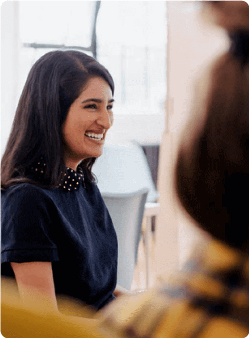 A woman talking in a conference room to co-workers.